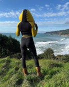 Fitted crop hoodie with cowl hood, yellow fabric with black accent, back side view worn by model.