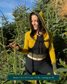 Fitted crop hoodie with cowl hood, yellow fabric with black and green accents, worn by female model.