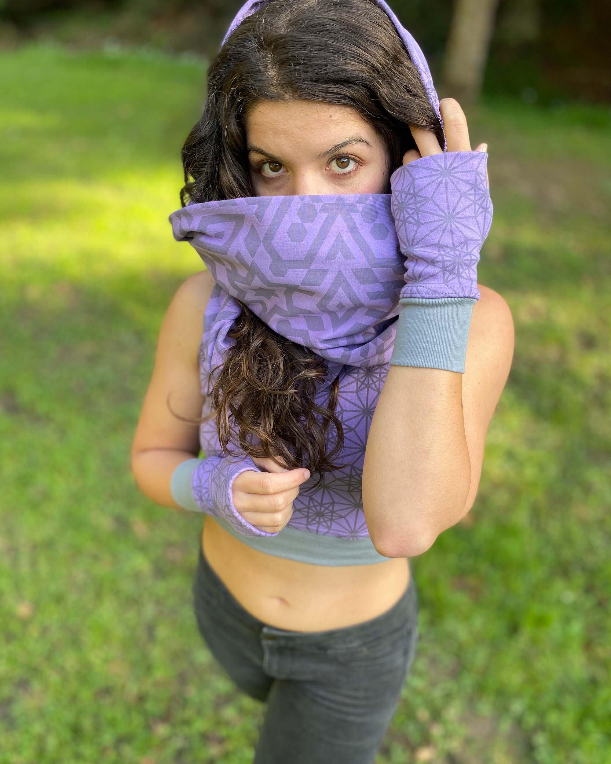 Female model wearing matching set of crop top, infinity scarf and fingerless gloves, purple organic cotton fabric with geo print, front view.