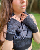 Female model wearing matching set of crop top, infinity scarf and fingerless gloves, black organic cotton fabric with geometric print, detail view of scarf.