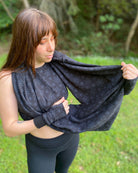 Female model wearing matching set of crop top, infinity scarf and fingerless gloves, black organic cotton fabric with geometric print, detail view of scarf.