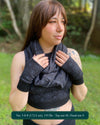 Female model wearing matching set of crop top, infinity scarf and fingerless gloves, black fabric with geometric print, front view.