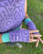 Female model wearing matching set of crop top, infinity scarf and fingerless gloves, lavender organic cotton fabric with geometric print, close up of gloves.