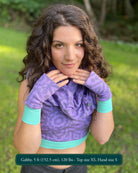 Female model wearing matching set of crop top, infinity scarf and fingerless gloves, lavender organic cotton fabric with geometric print, front view.
