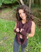 Female model wearing matching set of crop top, infinity scarf and fingerless gloves, brown organic cotton fabric with geometric print, front right side view.