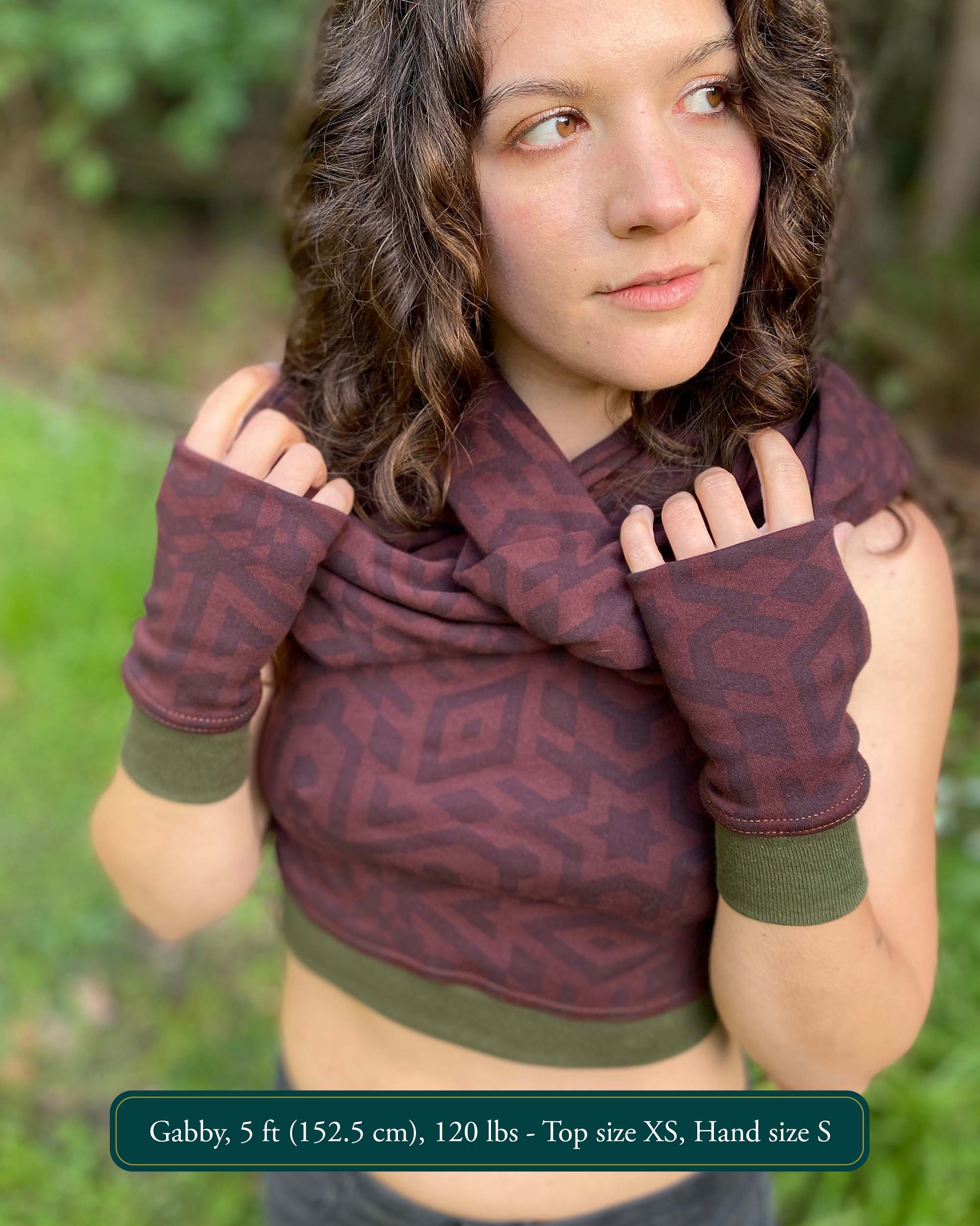 Female model wearing matching set of crop top, infinity scarf and fingerless gloves, brown organic cotton fabric with geometric print, front view.