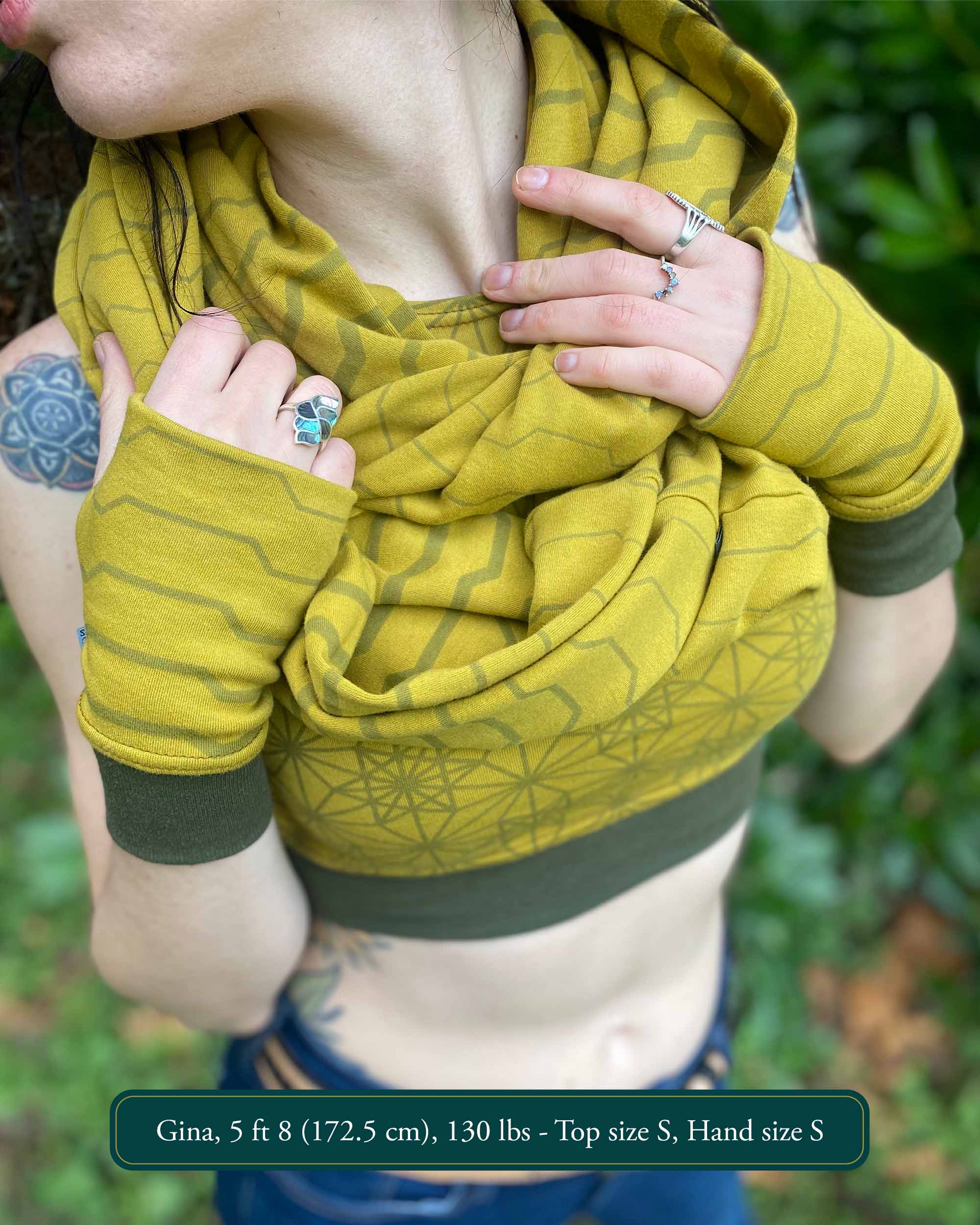 Female model wearing matching set of crop top, infinity scarf and fingerless gloves, yellow organic cotton fabric with geometric stripes, detail view.