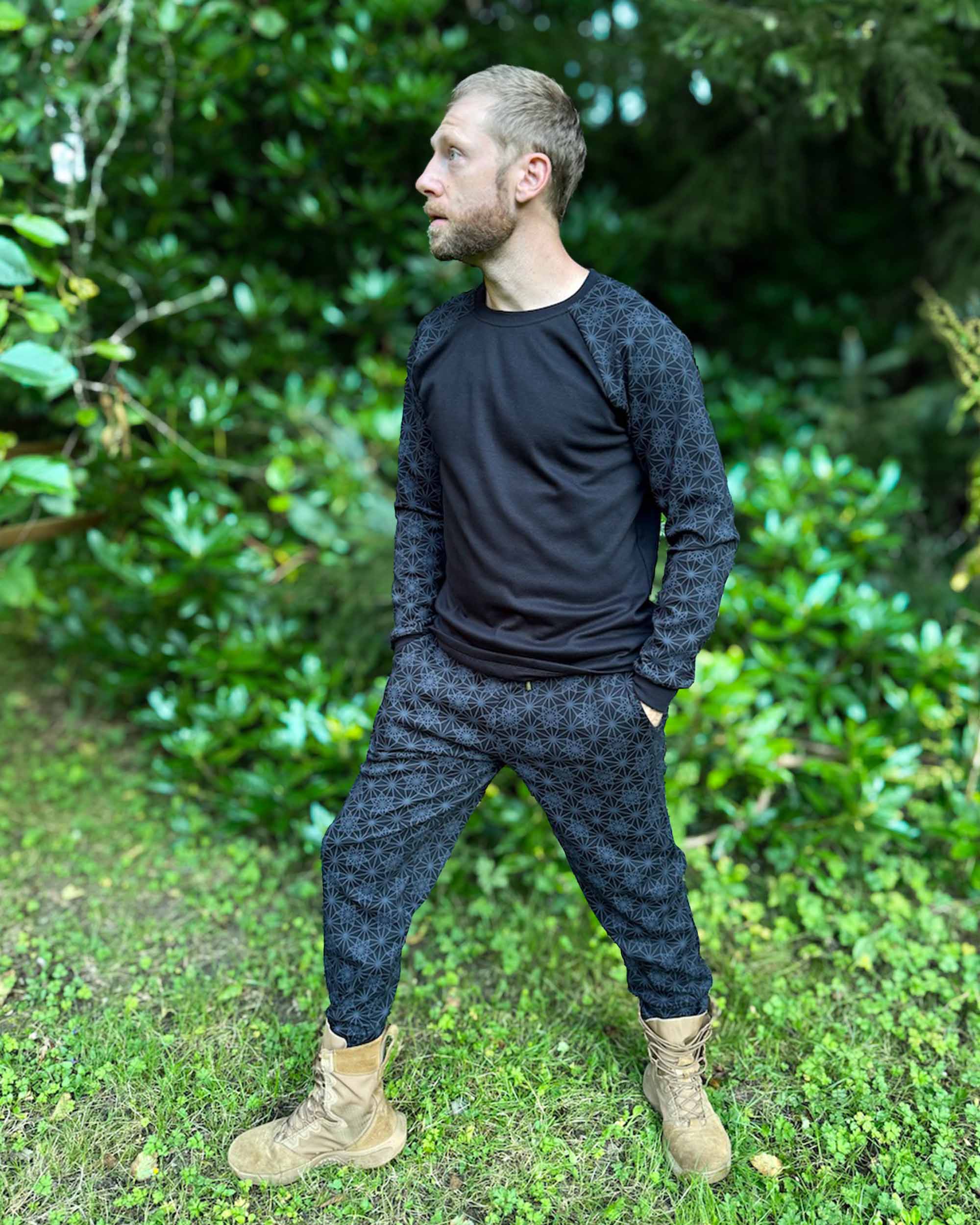 Men's matching joggers and long sleeve shirt, black with geometric printed accent fabric, worn by male model in nature.
