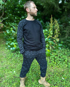 Men's matching joggers and long sleeve shirt, black with geometric printed accent fabric, side view on male model.