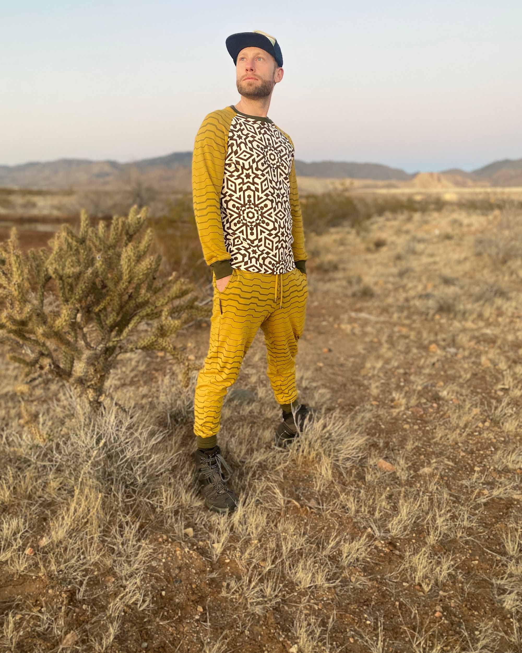 Men's matching joggers and long sleeve shirt, yellow with geometric stripe accents, worn by male model in desert.