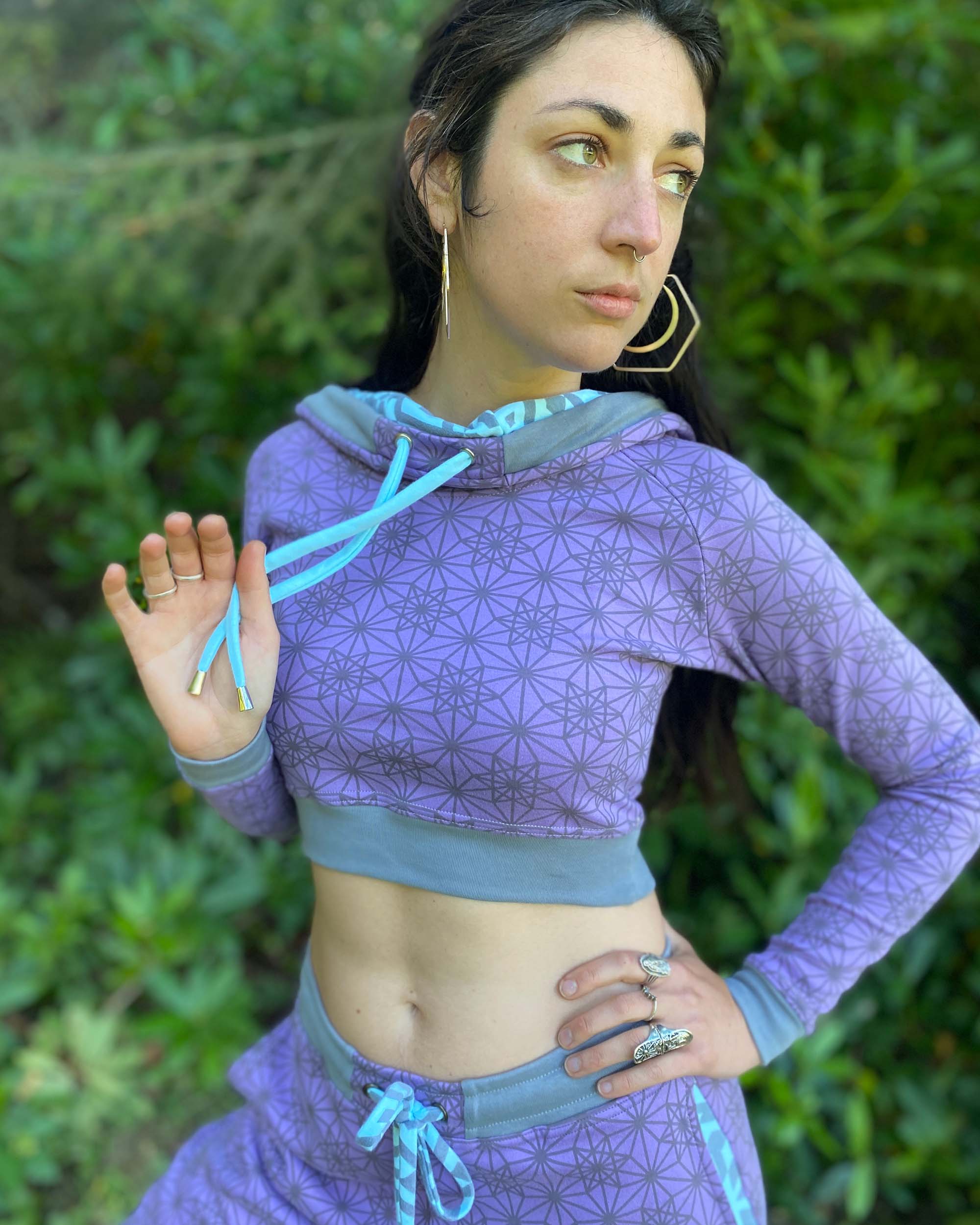 Matching two piece set, joggers and crop hoodie, lavender with geometric printed fabric, view from waist up on female model.