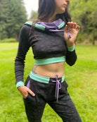 Women's matching two piece set, joggers and crop hoodie, black fabric with lavender geometric accents, front view.