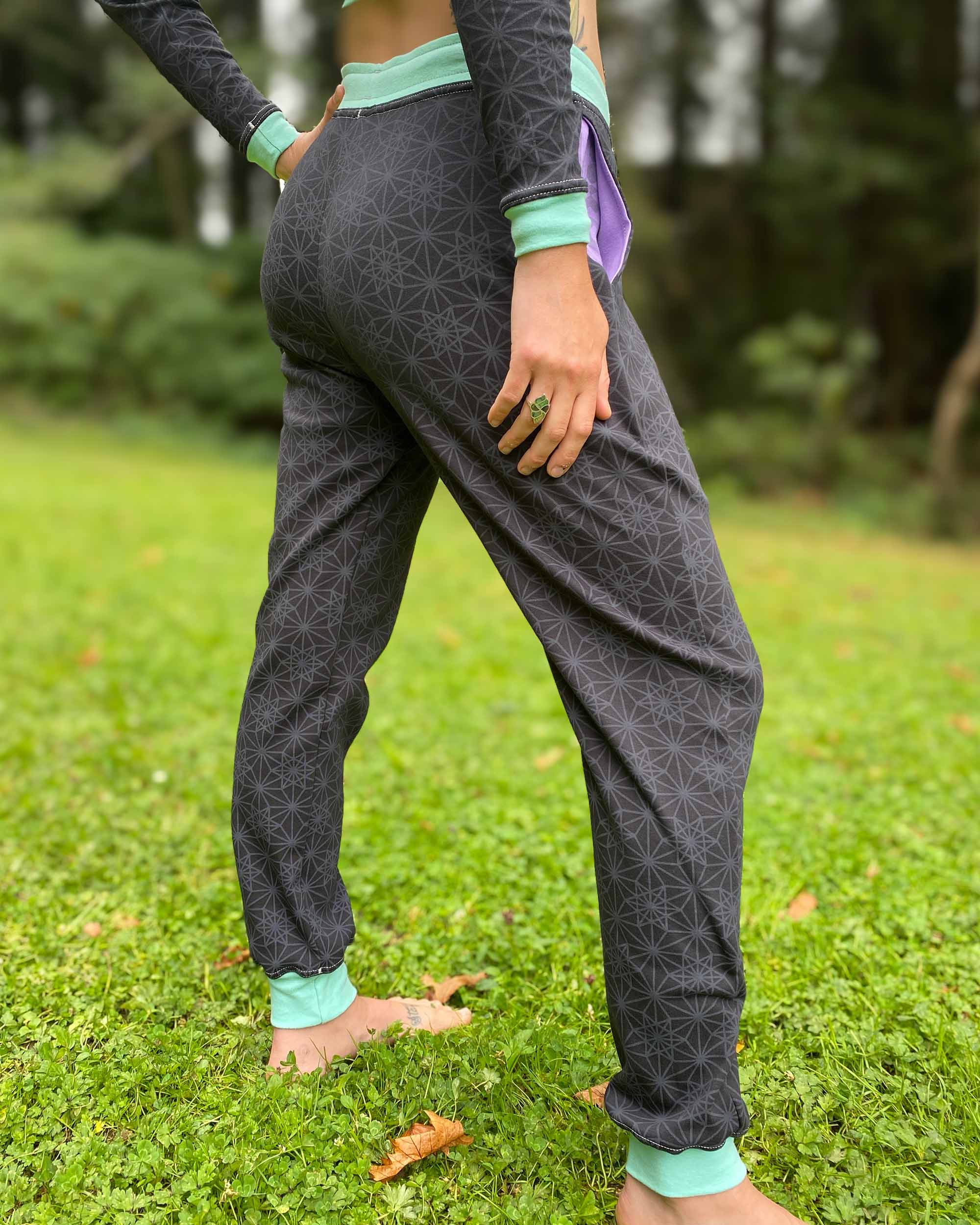 Organic cotton joggers, black and lavender fabric with geometric print, right back side view on female model. 