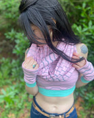Organic cotton crop top, pink fabric with grey geometric print, top view of model in nature.