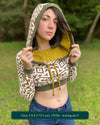 A woman wearing an organic cotton undyed crop hoodie with brown geometric printed fabric and green accents, front view.