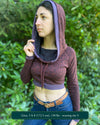 A woman wearing an organic cotton brown crop hoodie with geometric print and purple accents, front side view.