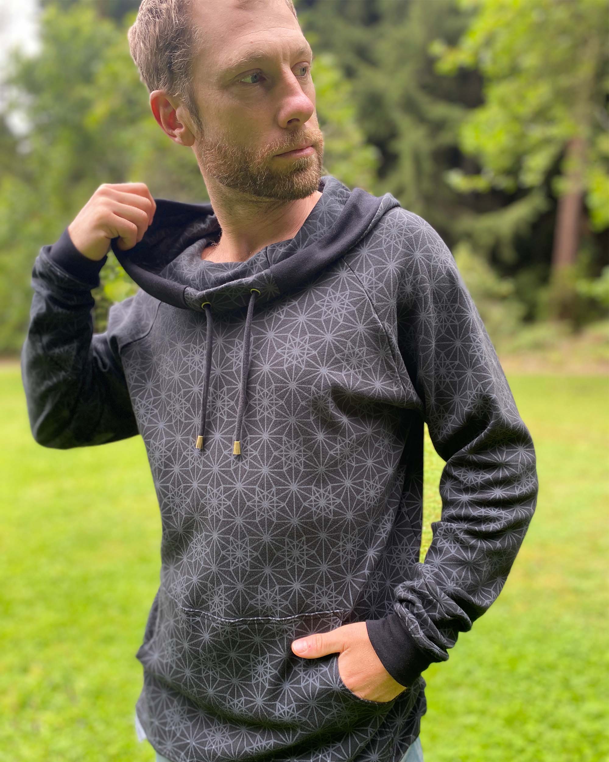 Organic cotton extra long unisex hoodie, black with sacred geometry print, left side view of male model.