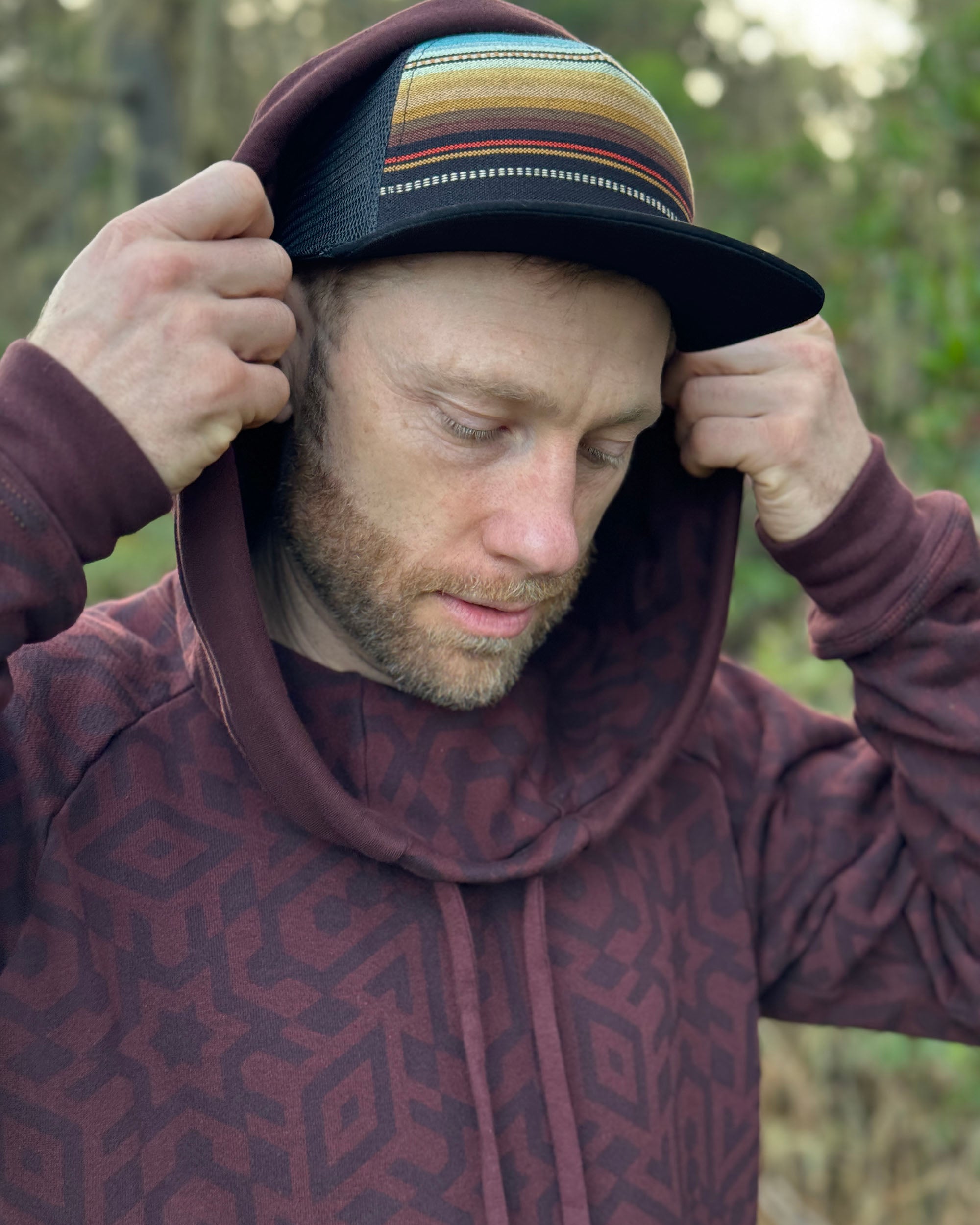 Organic cotton fleece unisex hoodie, reddish brown fabric with geometric print, front close up view of hood.