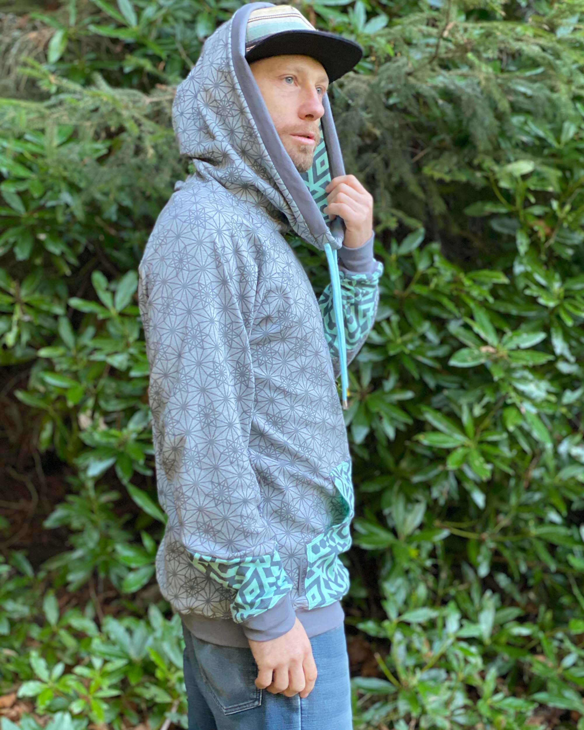 Organic cotton extra long unisex hoodie, grey fabric with geometric print, right side view of male model.