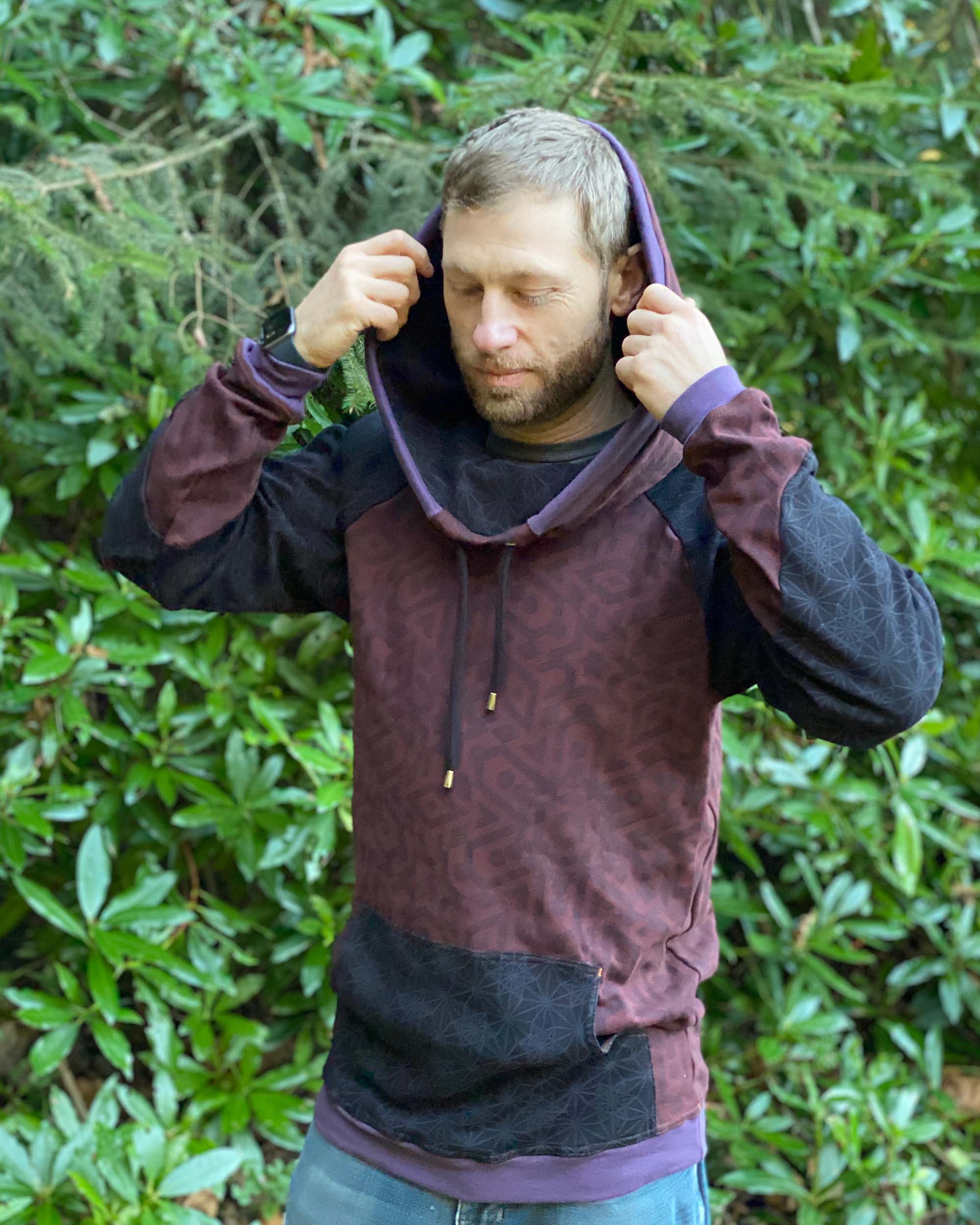 Organic cotton hoodie, reddish brown fabric with sacred geometry print, front view of male model.