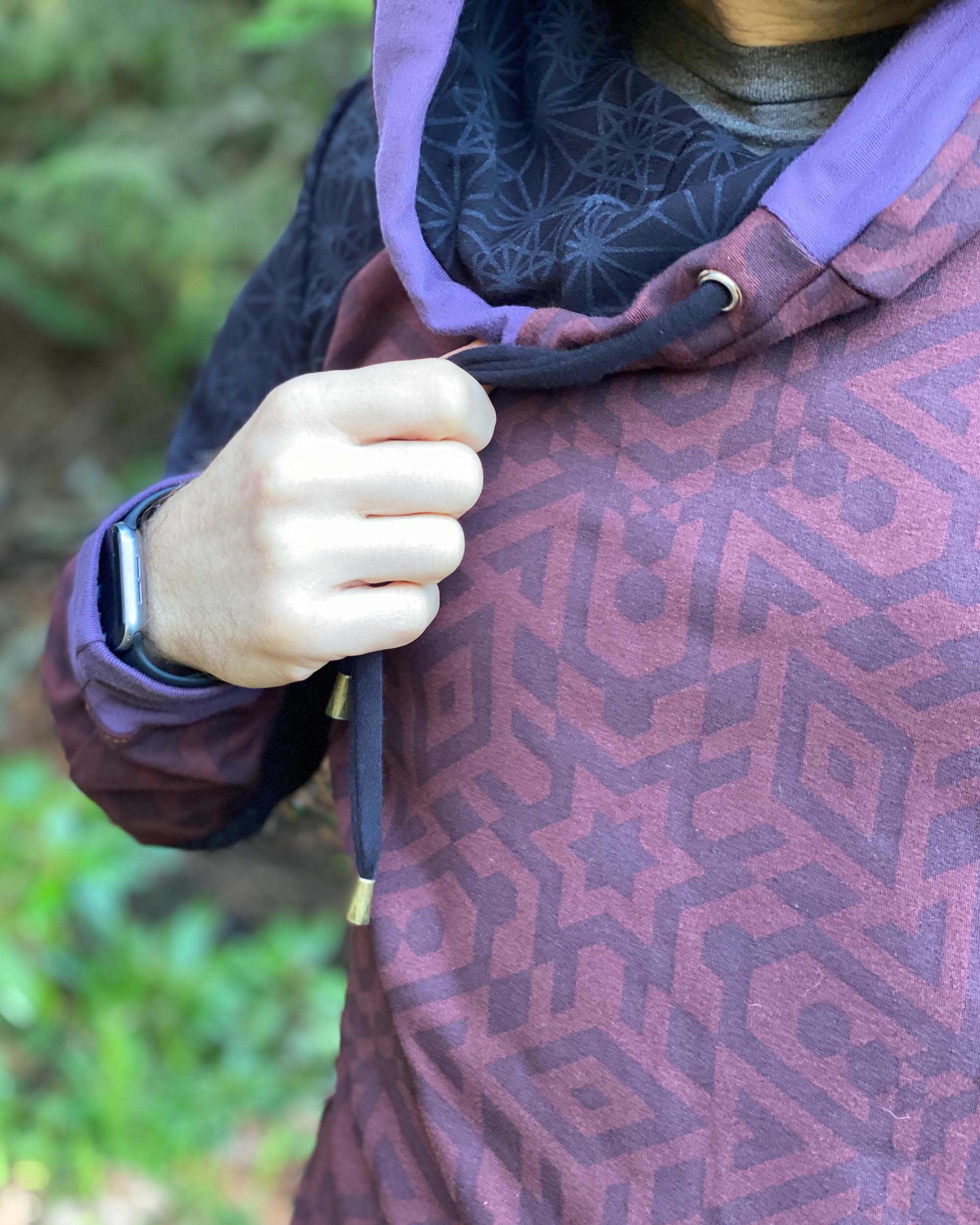 Organic cotton hoodie, reddish brown fabric with sacred geometry print, detail view of fabric.