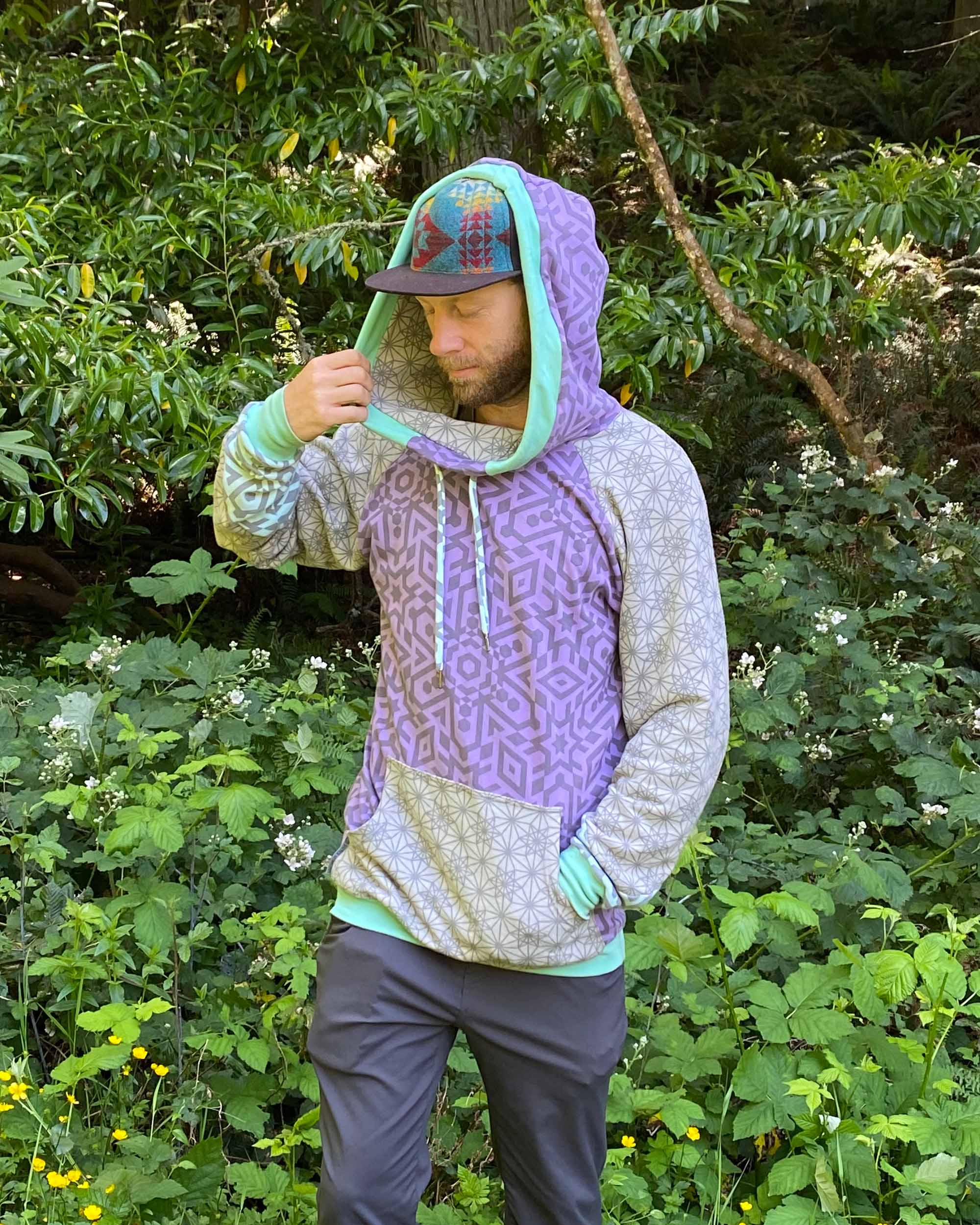 Organic cotton hoodie, lavender and pink fabric with geometric print, left side view on male model.