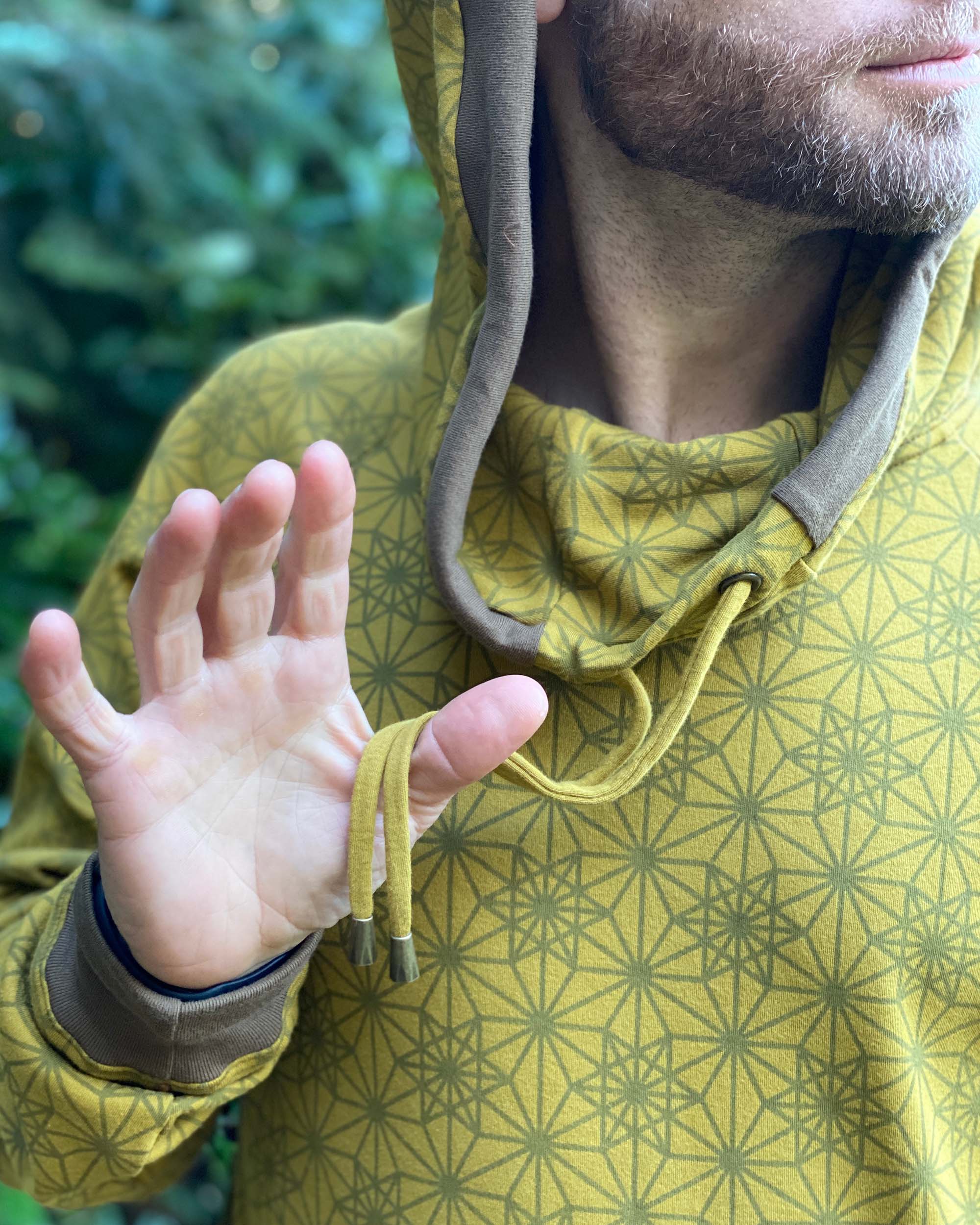 Organic cotton extra long unisex hoodie, yellow fabric with geometric print, detail close up of drawcord.