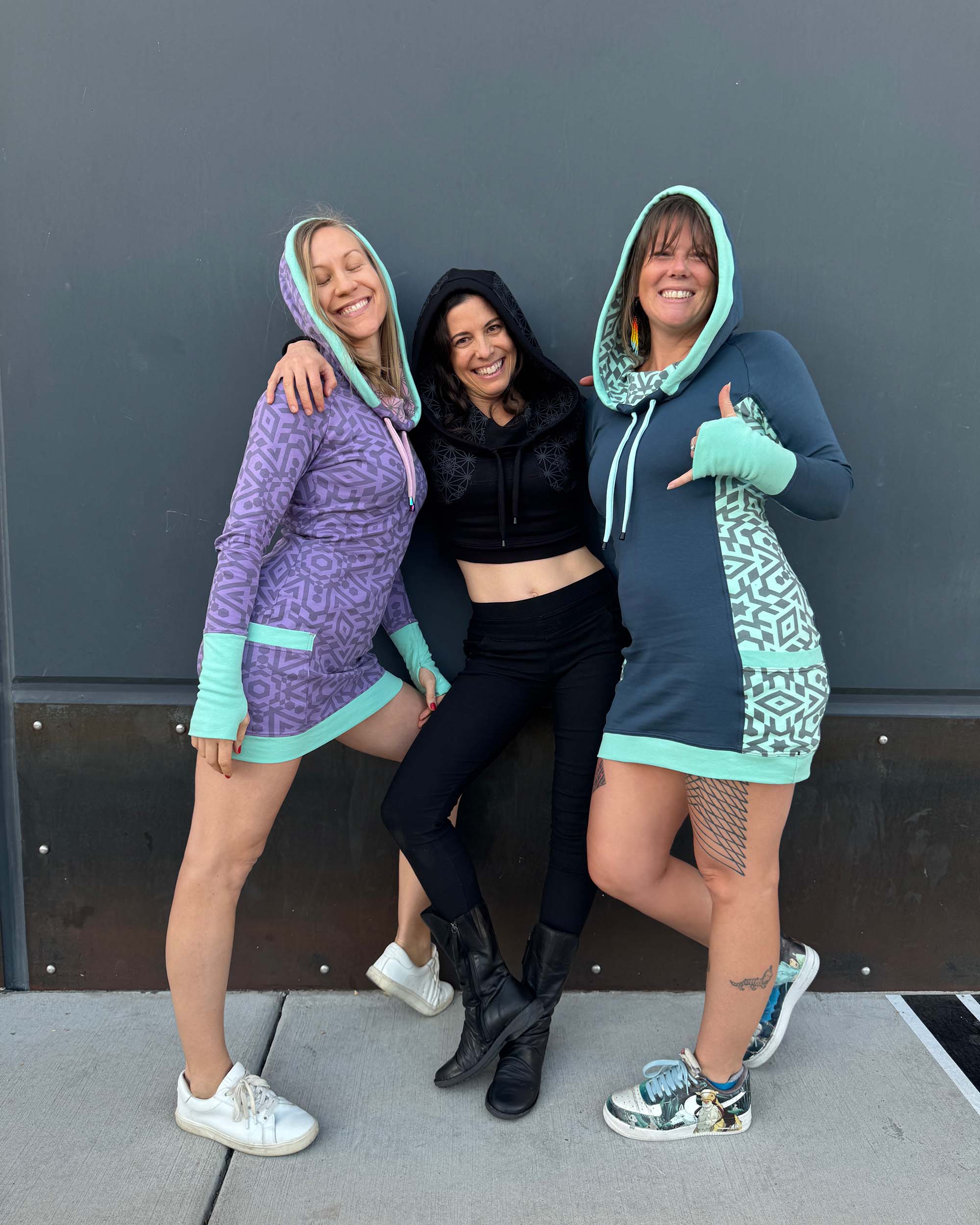 3 models wearing organic cotton hooded dresses in multiple colors with geometric fabric prints.