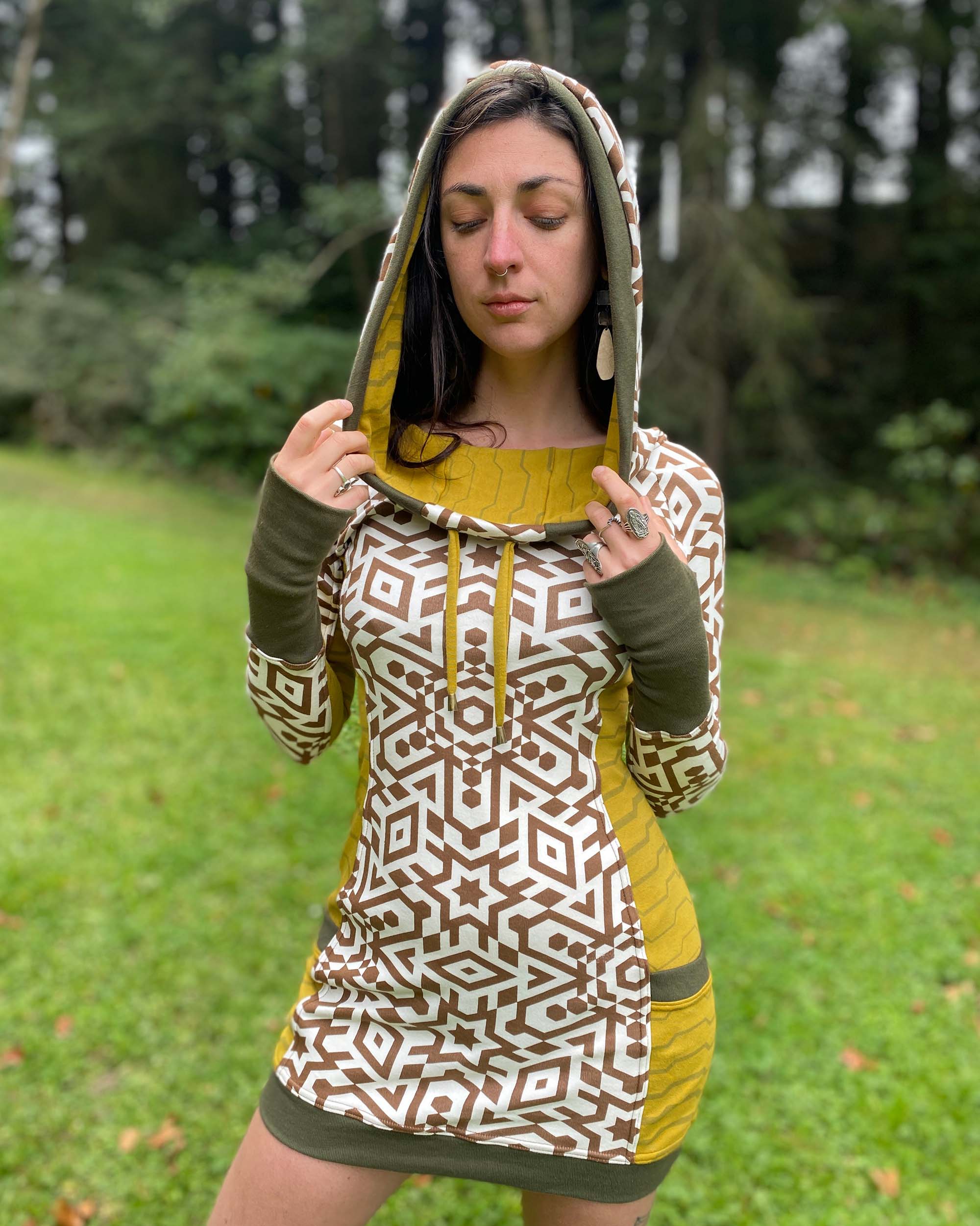 Organic cotton hooded tunic dress, undyed and yellow fabric with geometric print, front view on model with hood up.
