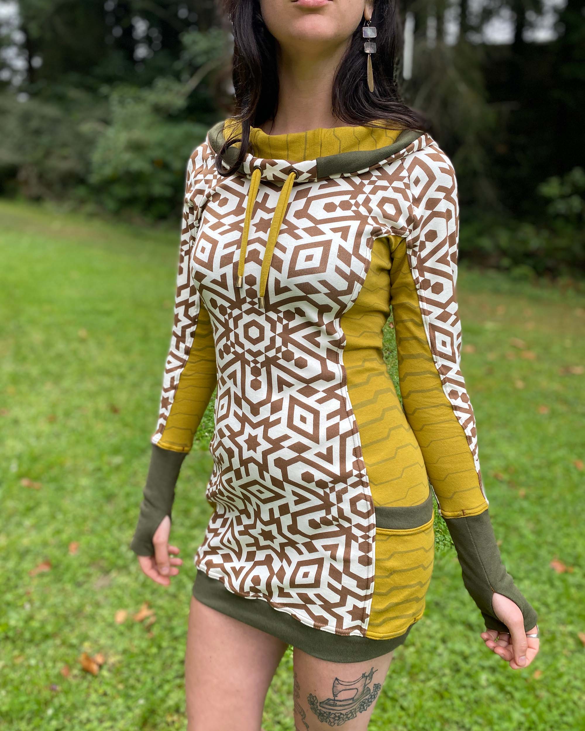Organic cotton hooded tunic dress, undyed fabric with brown geo print and yellow accents, close up view of fabric.