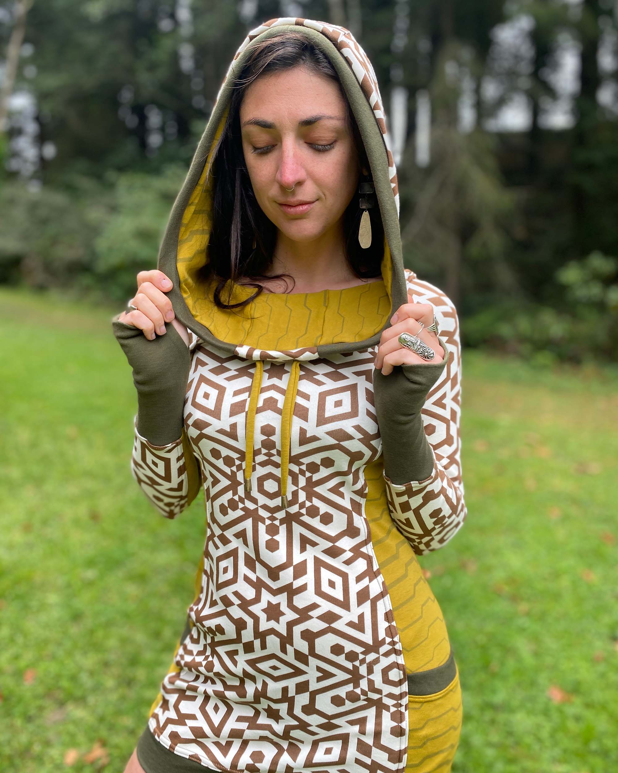 Organic cotton hooded tunic dress, undyed fabric with brown geo print and yellow accents, close up view on model.