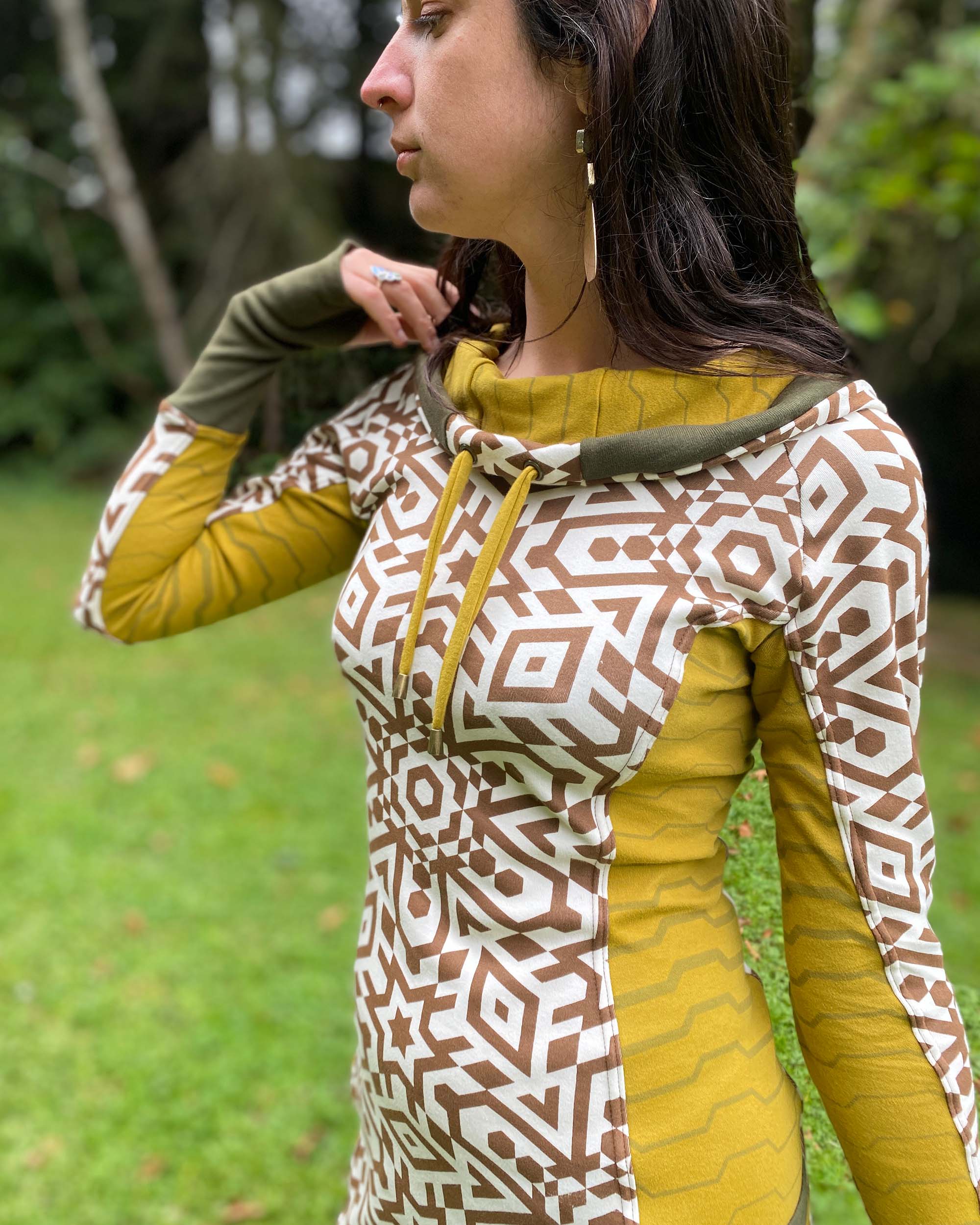 Organic cotton hooded tunic dress, undyed fabric with brown geo print and yellow accents, front left view on model.