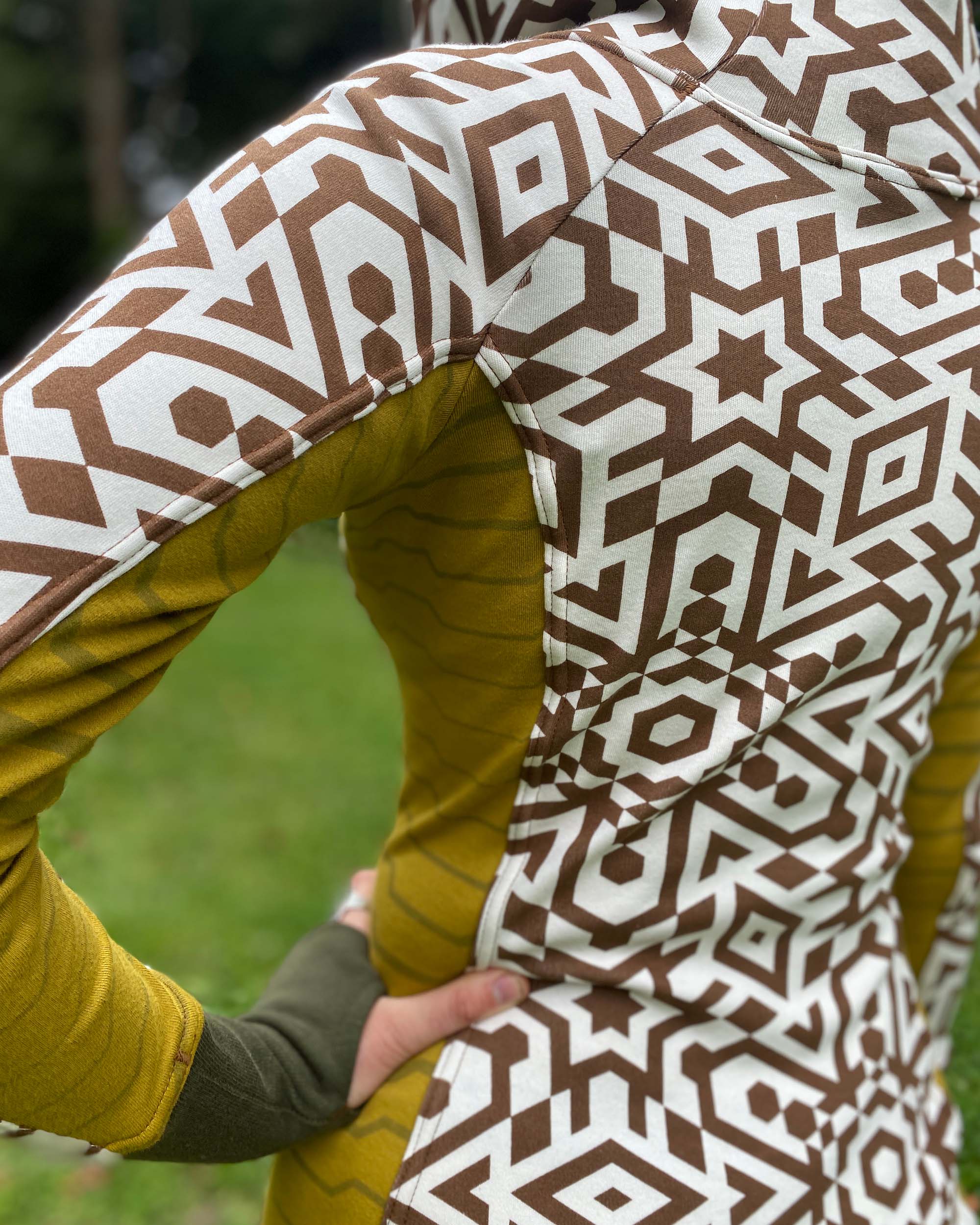Organic cotton hooded tunic dress, undyed fabric with brown geo print and yellow accents, detail view of fabric print.