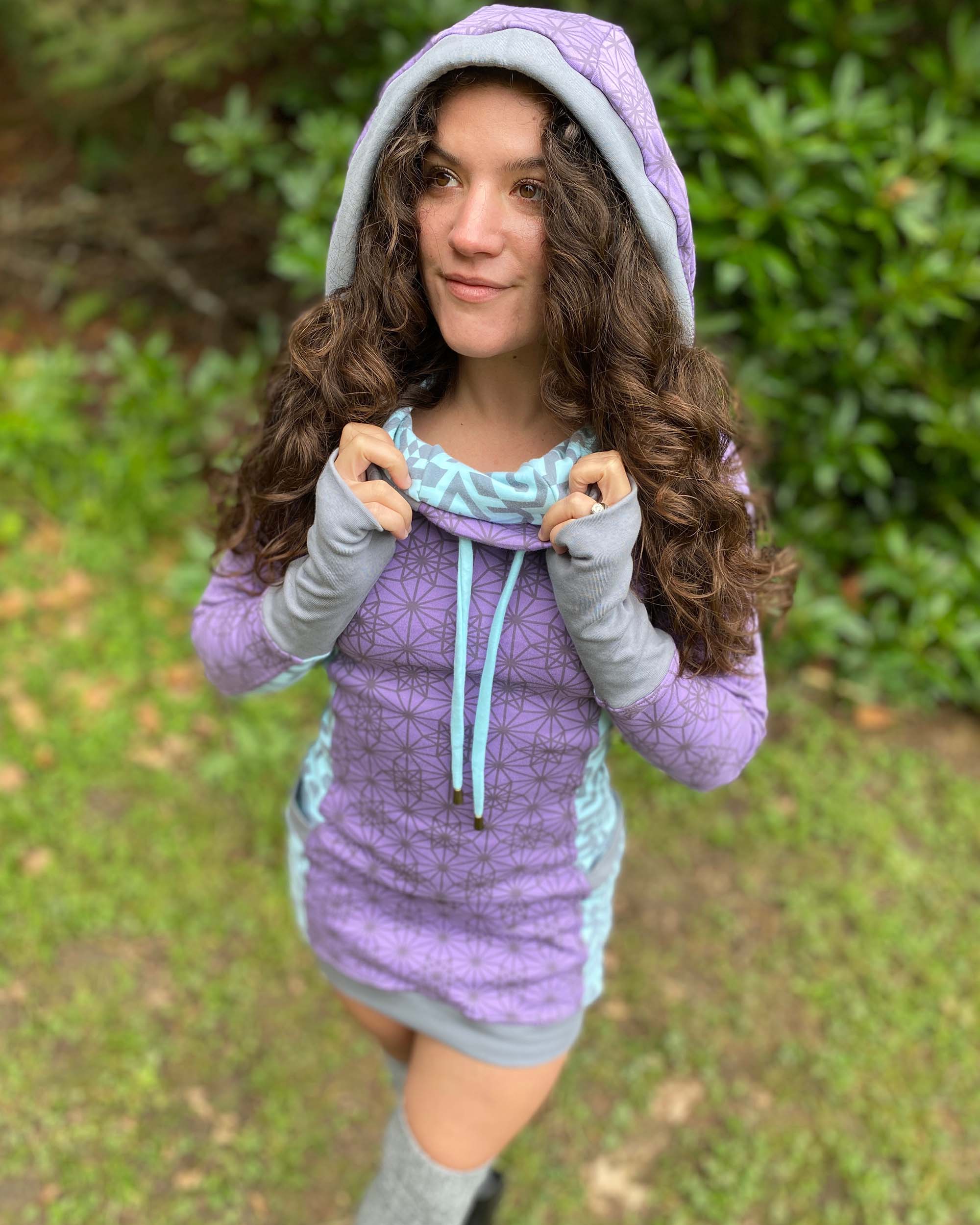 Organic cotton hooded tunic dress, lavender with geometric mint fabric accents, front top view on model.