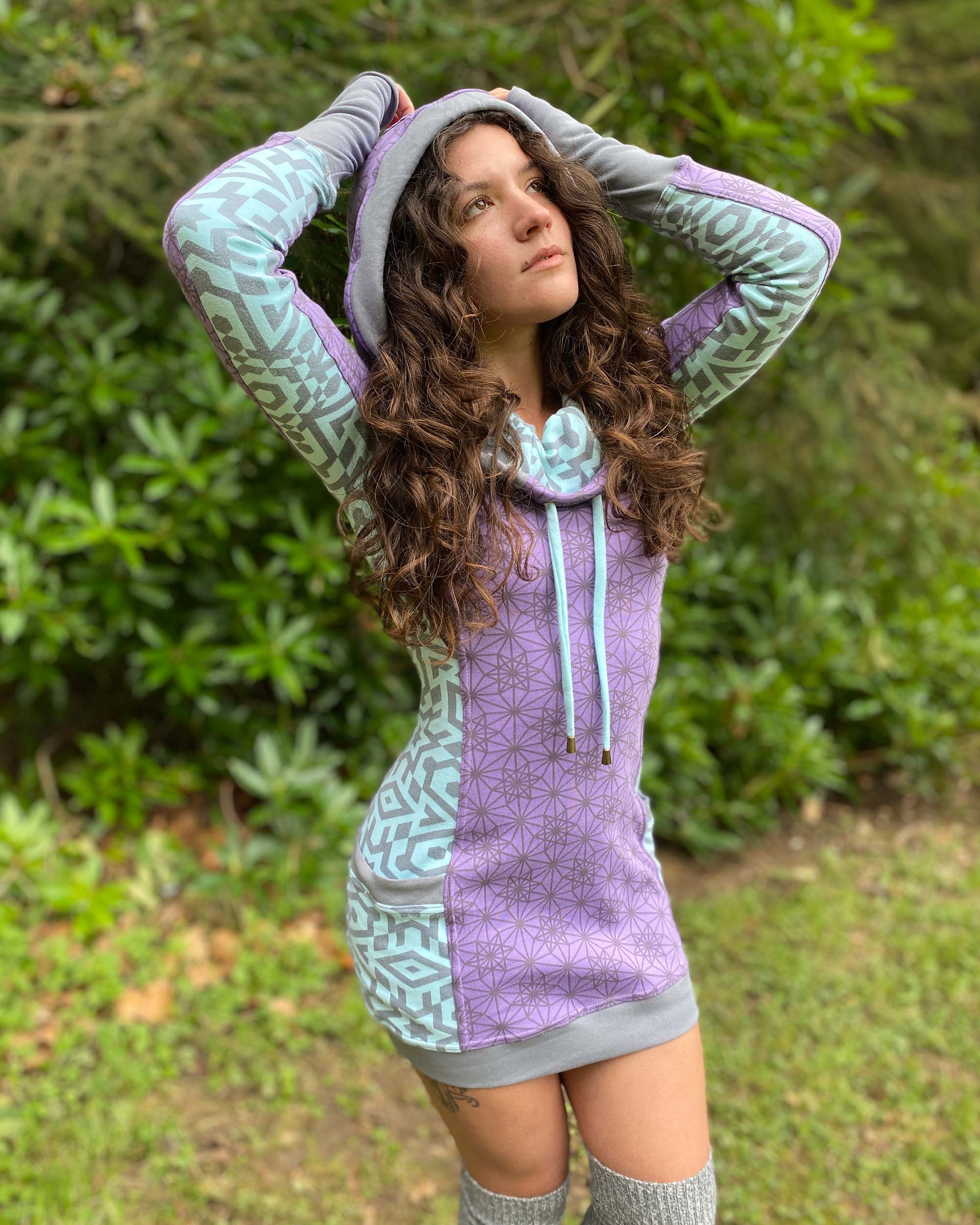 Organic cotton hooded dress, lavender and mint fabric with geometric print, front view on model, hood up.
