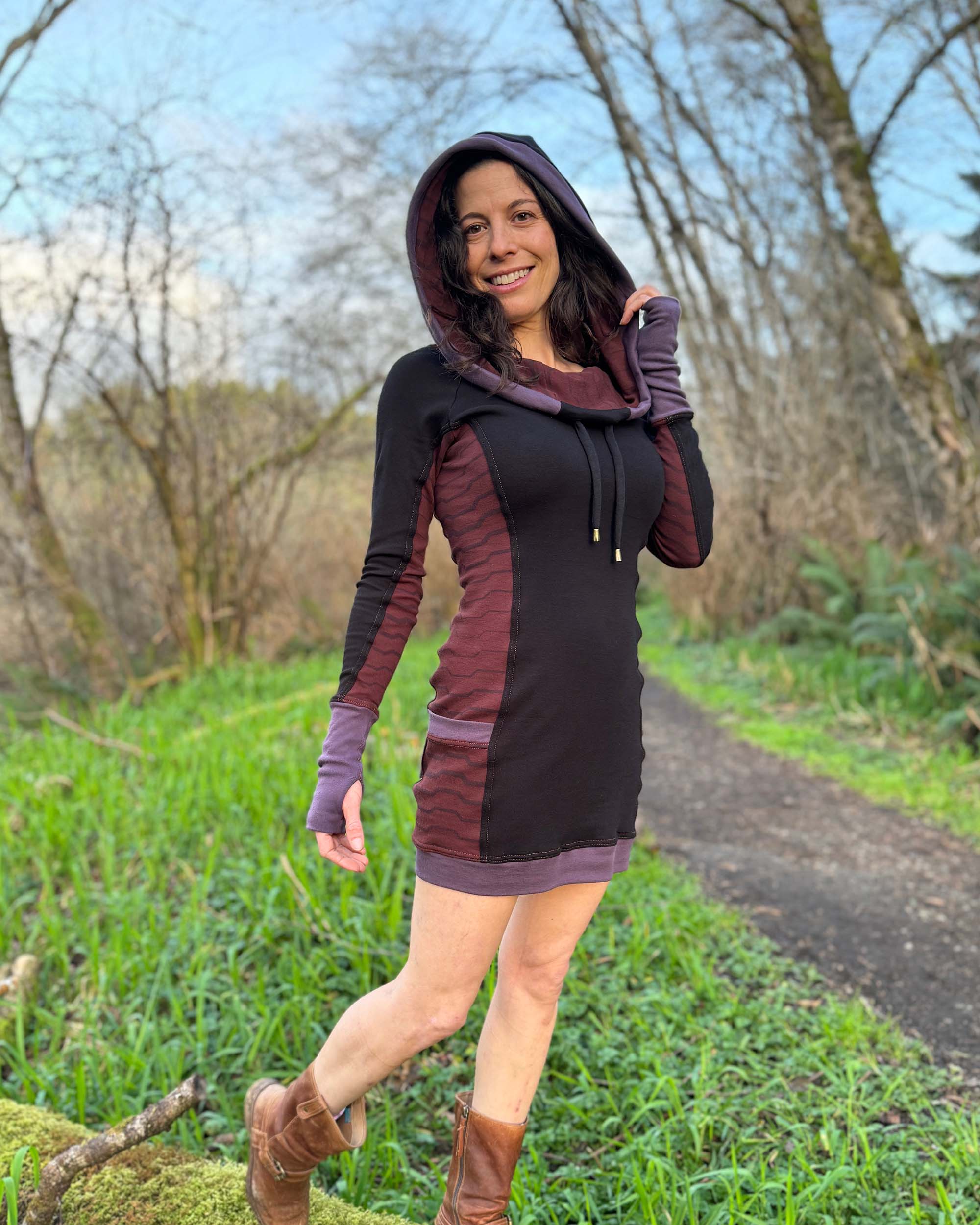 Organic cotton hooded tunic dress, black with geometric brown fabric accents, front right side view on model.
