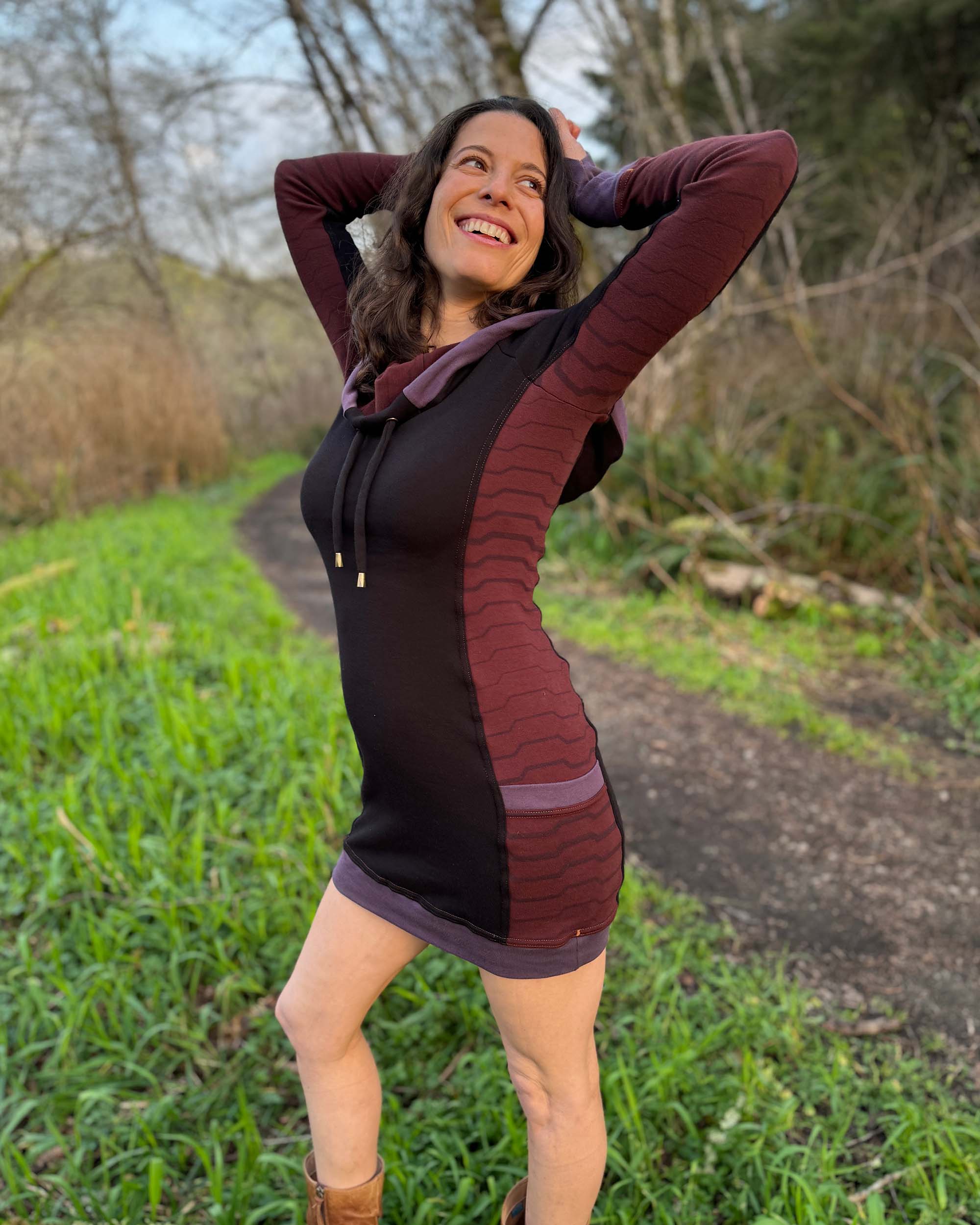 Organic cotton hooded tunic dress, black with geometric brown fabric accents, front left side view on model.