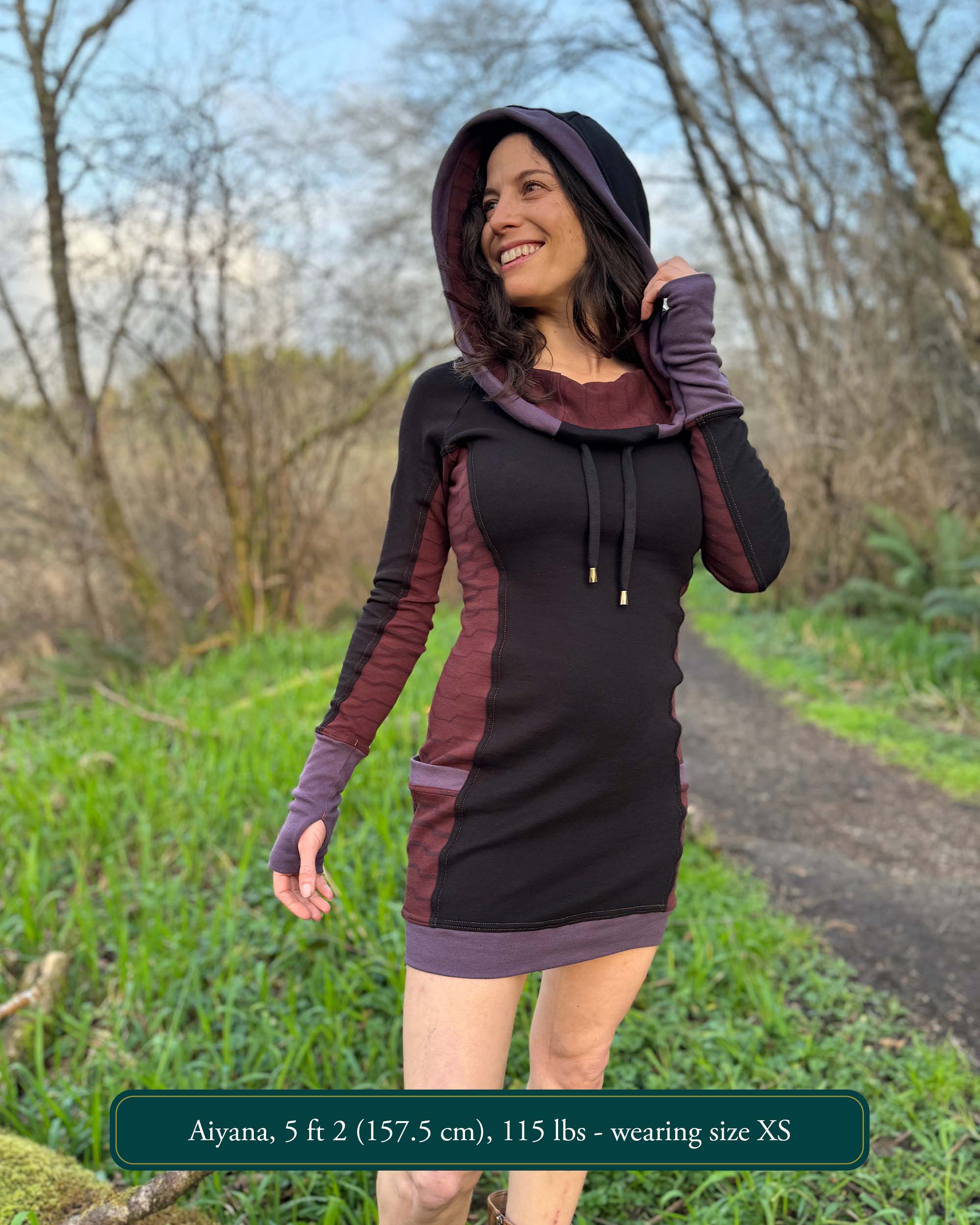 Organic cotton hooded tunic dress, black with geometric brown fabric accents, front view on model.