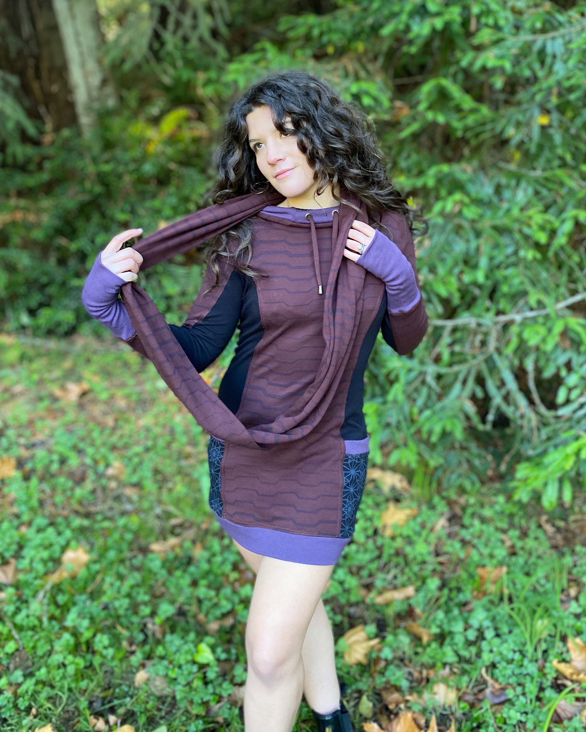 Organic cotton hooded tunic dress, reddish brown with geometric black fabric accents, front view on model.