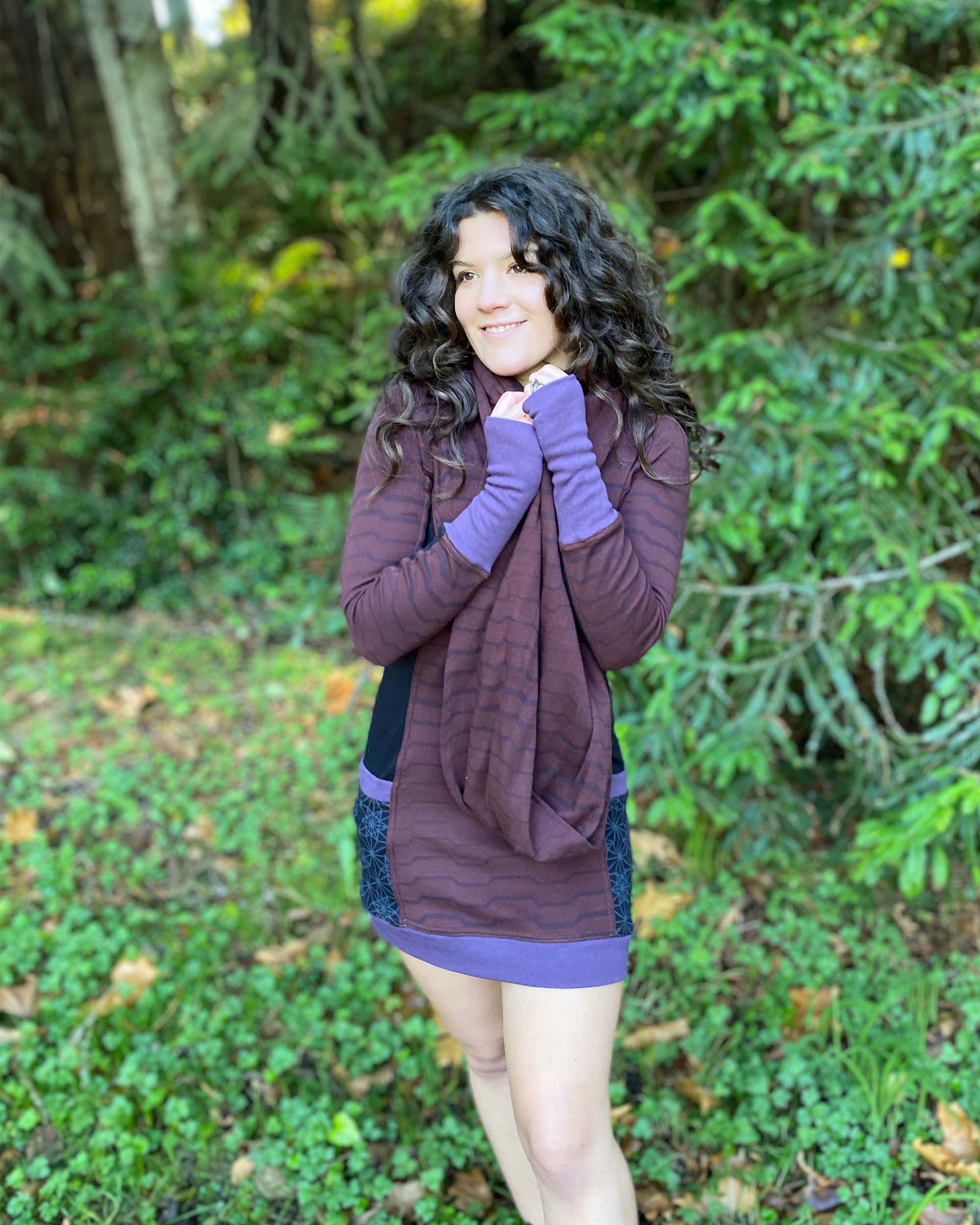 Organic cotton hooded tunic dress, reddish brown with black fabric accents, back view on model.