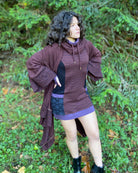 Organic cotton hooded tunic dress, reddish brown with geometric black fabric accents, front right side view on model.