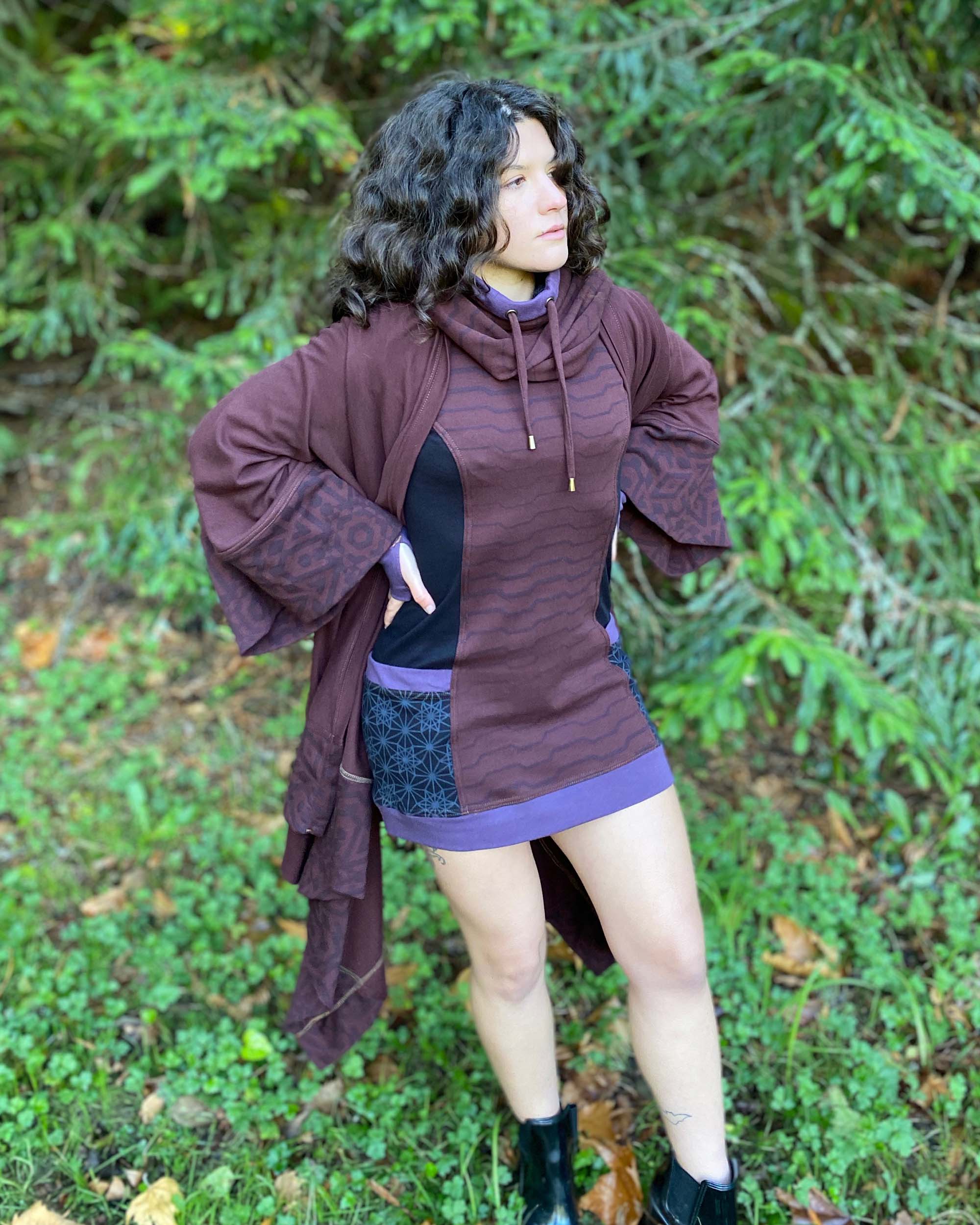 Organic cotton hooded tunic dress, reddish brown with geometric black fabric accents, front right side view on model.