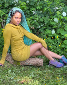 Organic cotton hooded tunic dress, yellow fabric with geometric print, right side view on sitting model.