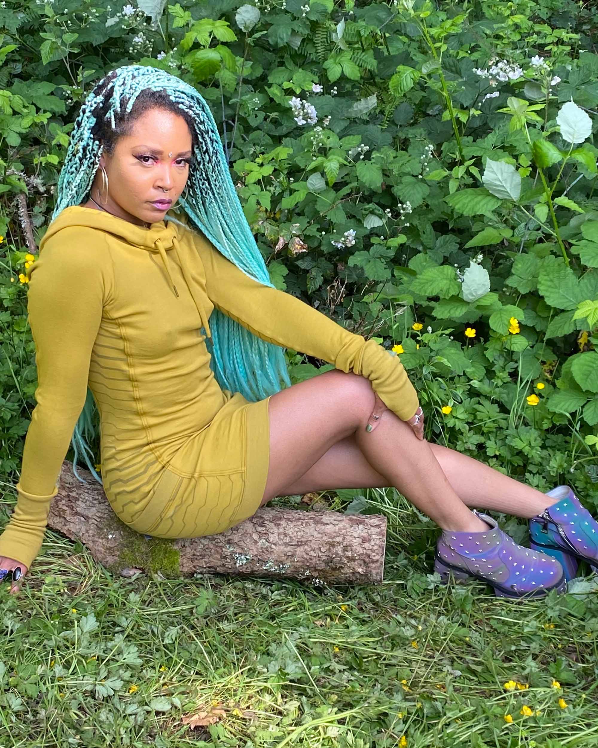 Organic cotton hooded tunic dress, yellow fabric with geometric print, right side view on sitting model.
