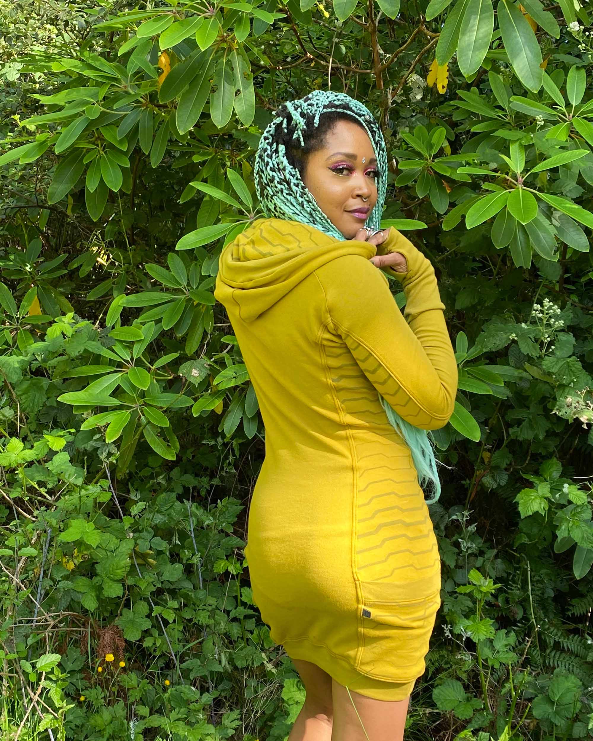 Organic cotton hooded tunic dress, yellow fabric with geometric print, back side view on model.