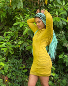 Organic cotton hooded tunic dress, yellow fabric with geometric print, left side view on model.