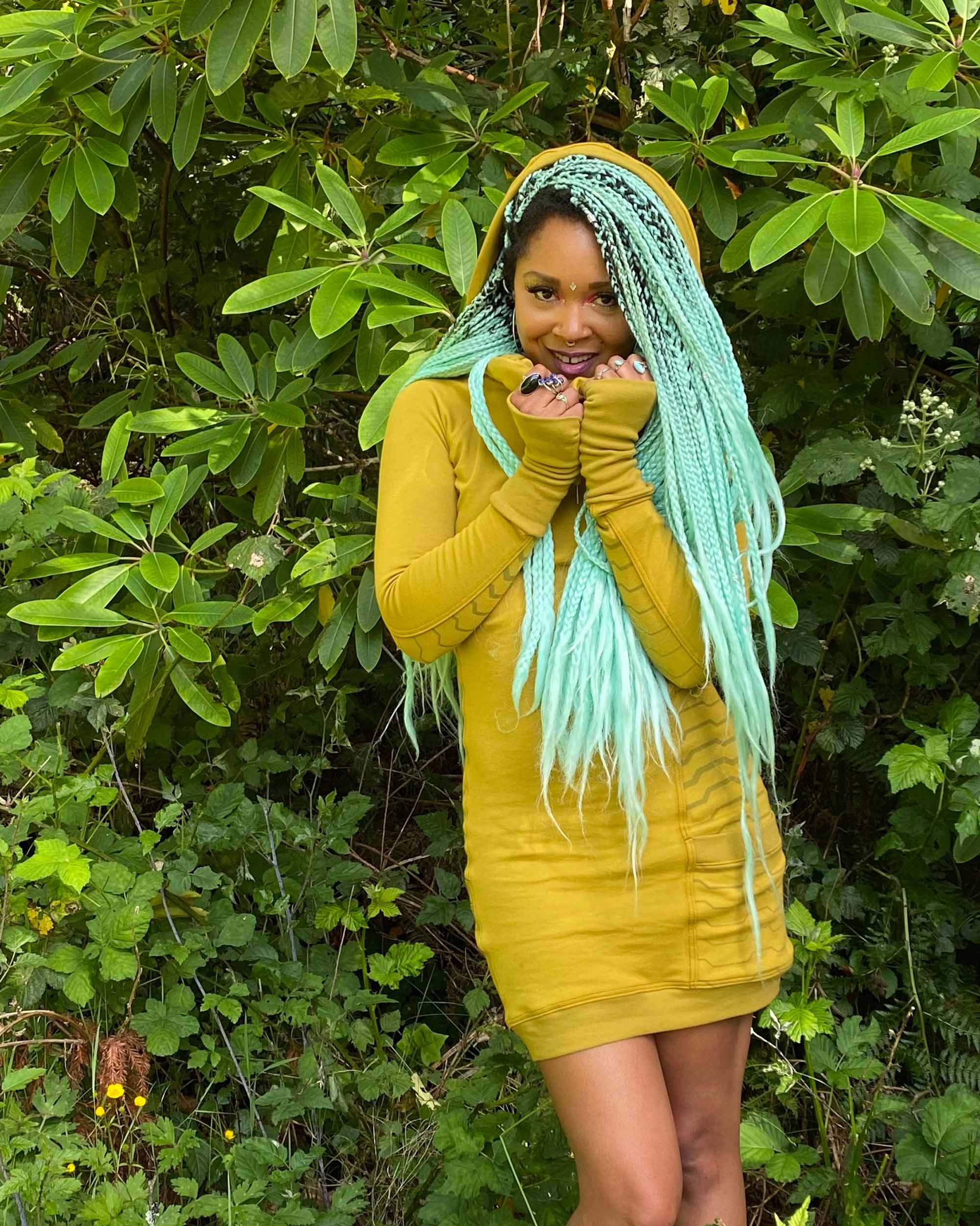 Organic cotton hooded tunic dress, yellow fabric with geometric print, front view on model in nature.