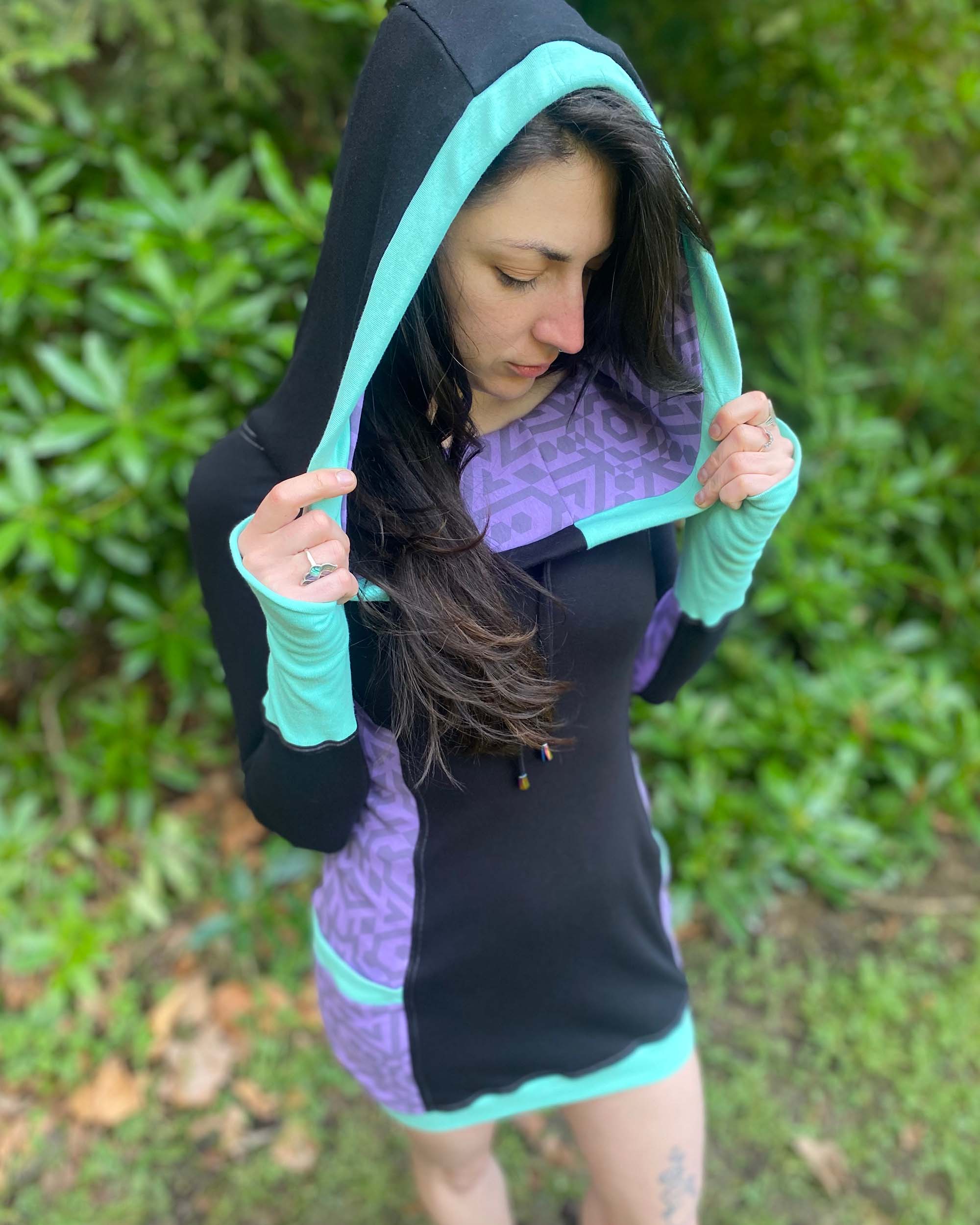 Organic cotton hooded tunic dress, black and lavender fabric with geometric print, top front view on model.