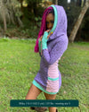 Organic cotton hooded tunic dress, lavender and pink fabric with geometric print, left side view on model.