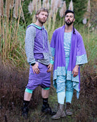 Two male models wearing Sacred Geometrix garments, lavender and grey fabric with geometric prints.